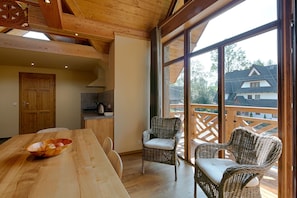 A dining area with a wooden table, wicker chairs, and a bowl of fruit. - Tatrzańskie Echo Domki Regionalne (Zakopane)