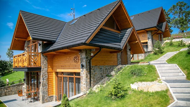 A modern log cabin with a stone facade, wooden balconies, and a stone staircase leading up to the entrance. - Tatrzańskie Echo Domki Regionalne (Zakopane)