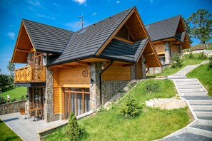 A modern log cabin with a stone facade, wooden balconies, and a stone staircase leading up to the entrance. - Tatrzańskie Echo Domki Regionalne (Zakopane)