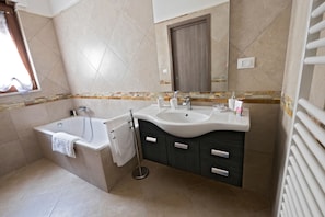 Un baño moderno con bañera, dos lavamanos, un mueble de tocador con cajones, un perchero para toallas y un espejo.