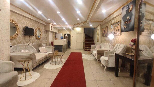Un vaste espace de vie agrémenté d’une moquette rouge, de plusieurs coins salon et d’un escalier menant à un autre niveau.