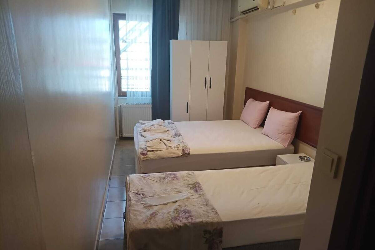 Hotellihuone, jossa on kaksi sänkyä, vaatekaappi ja patteri.