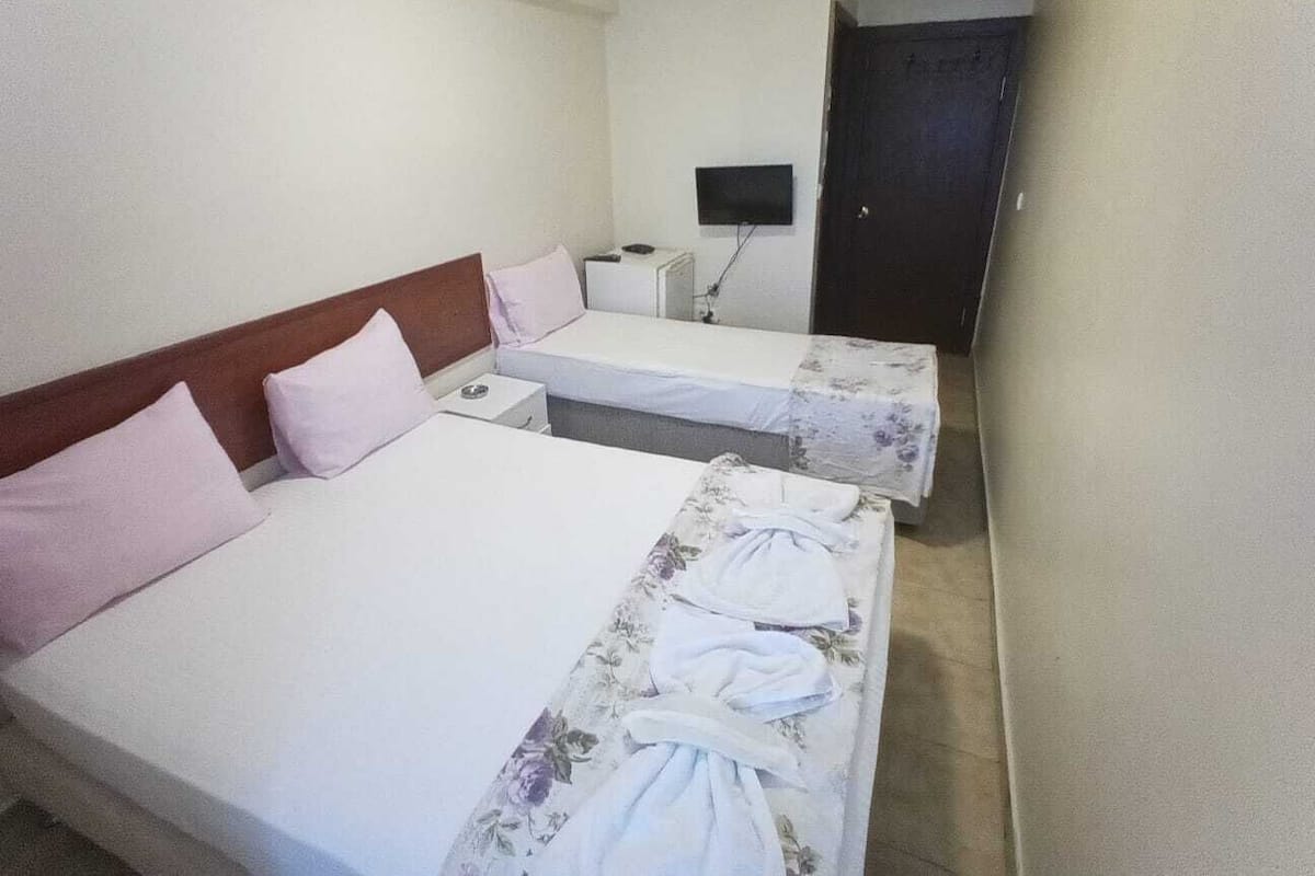 Hotellihuoneessa on kaksi sänkyä, joissa on molemmissa puinen pääty ja valkoiset vuodevaatteet. Huoneessa on myös pieni työpöytä, jossa on lamppu, sekä seinälle asennettu litteänäyttöinen televisio.