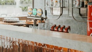 A bar area with a counter, shelves with bottles, and a hanging light fixture.