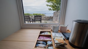 A wooden bench with a window view of a rocky landscape and chairs outside. - Summer Isles Hotel (Ullapool)