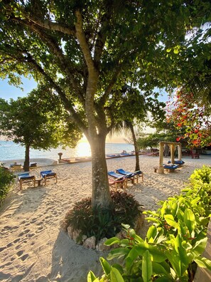 På stranden, vit sandstrand, solstolar och strandhanddukar