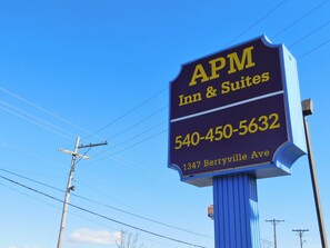 A sign for APM Inn & Suites with a phone number and address.