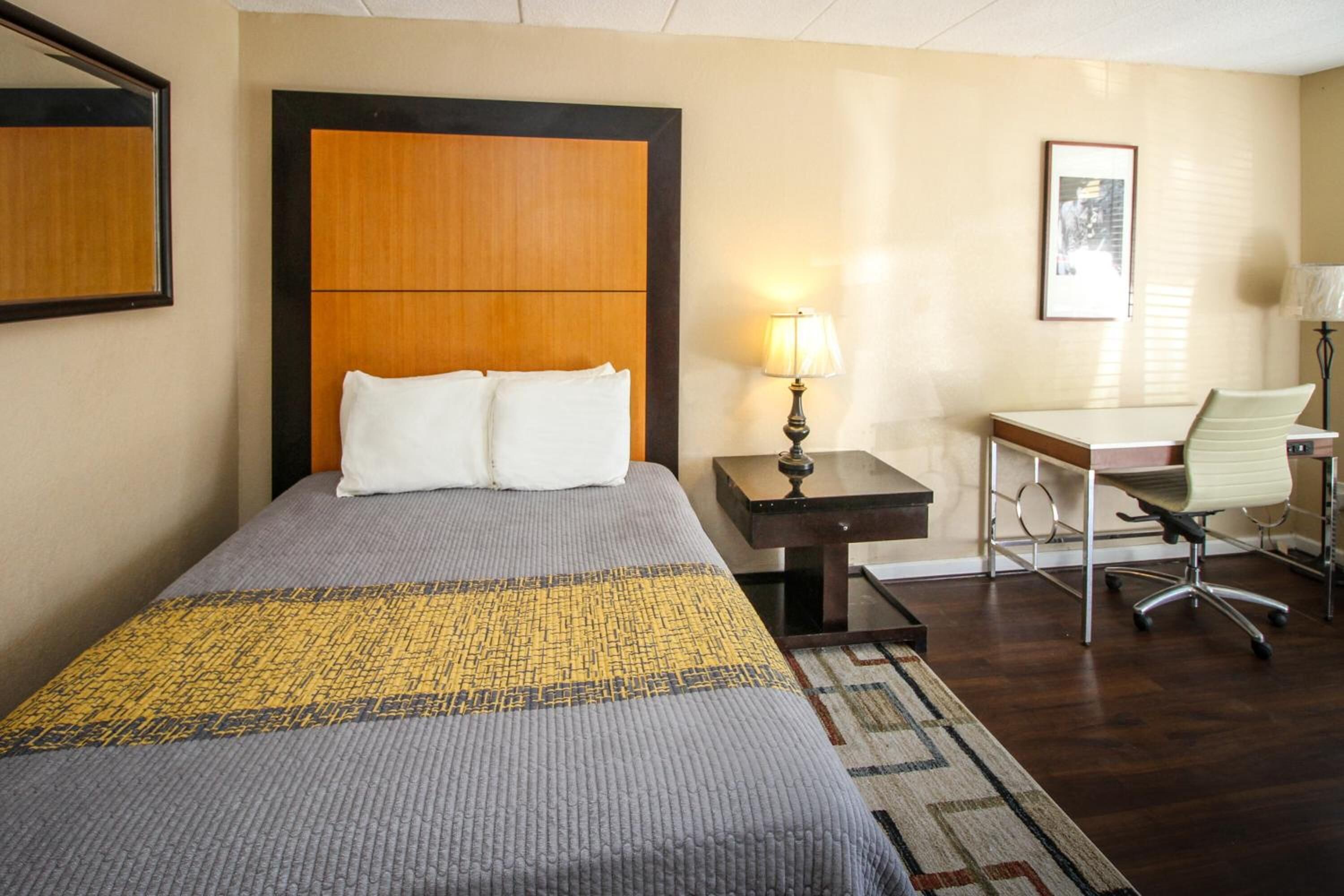 Una habitación de hotel con una cama grande, un escritorio, una silla y una lámpara.