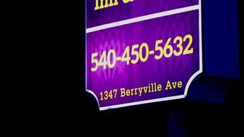 Une enseigne au néon pour l’hôtel APM Inn & Suites, avec l’adresse 1347, avenue Berryville, et le numéro de téléphone 540-450-5632.