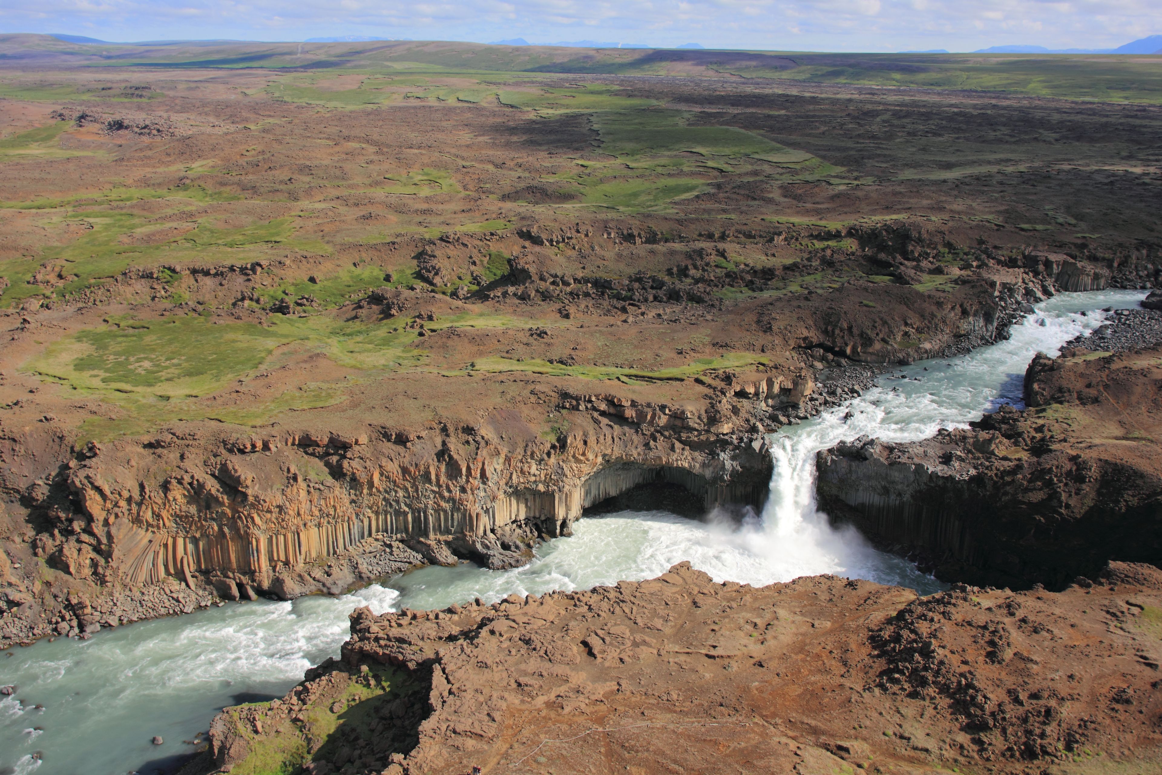 A river flowing through a rugged landscape with a waterfall.