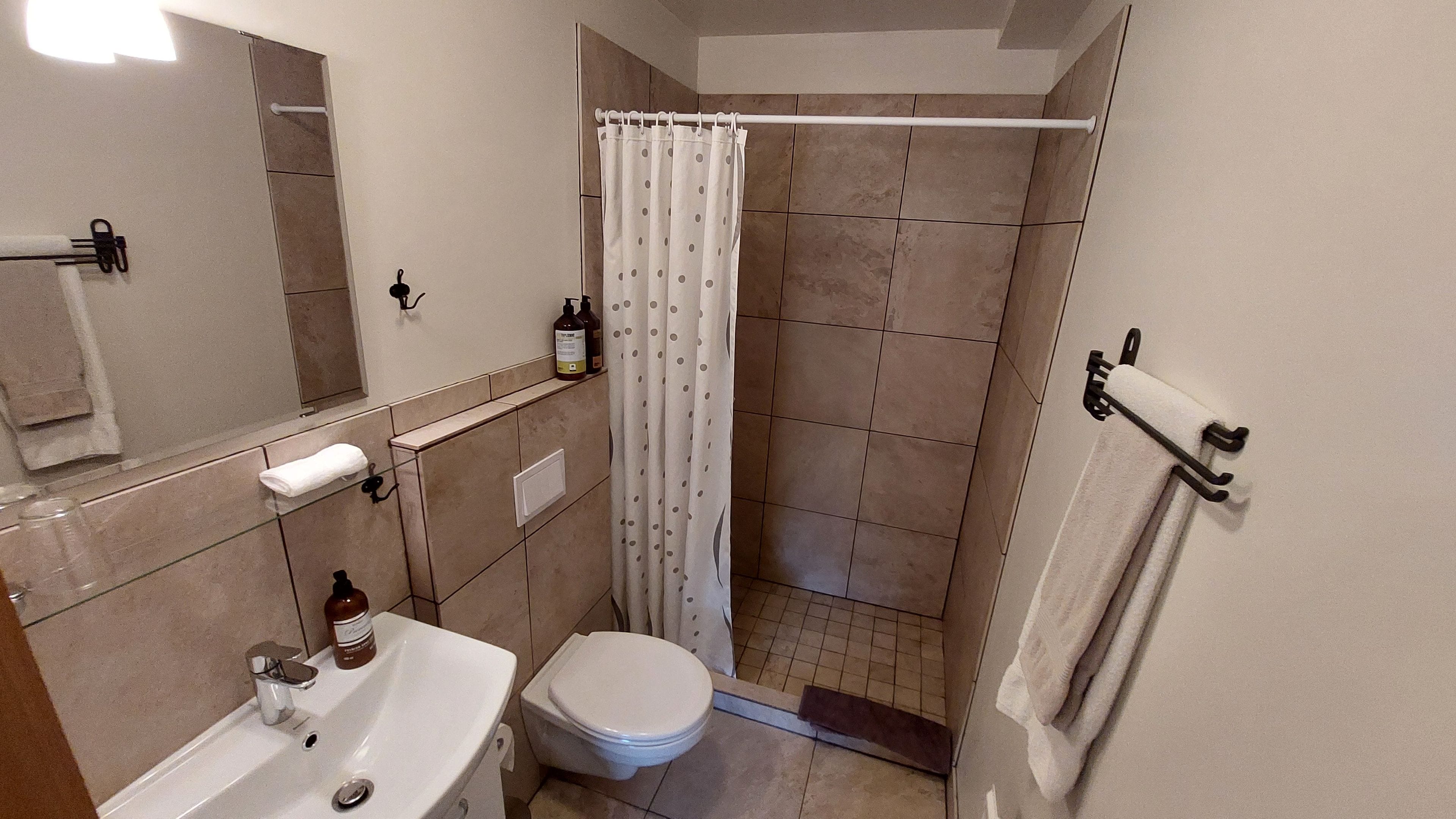 Un baño con inodoro, lavamanos y cortina de ducha.