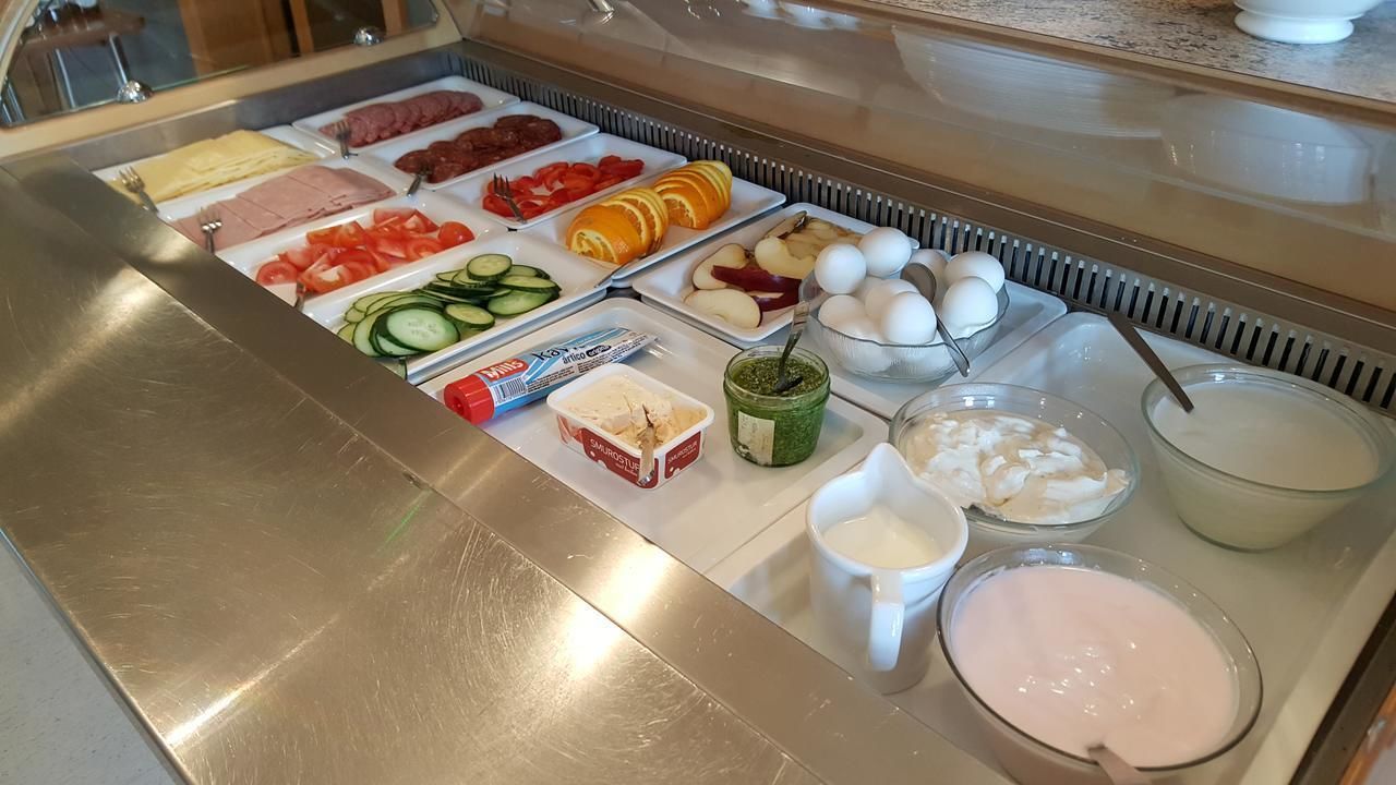 A buffet with various food items including meats, fruits, and eggs.