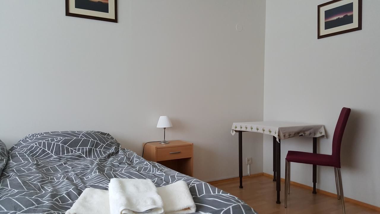 Ein Schlafzimmer mit einem Bett, einem Nachttisch, einem Tisch mit Stuhl und zwei gerahmten Bildern an der Wand.