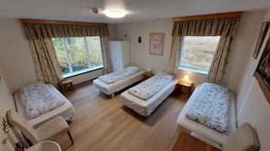 A room with three single beds, a wooden desk, a chair, and a window with curtains. - Kiðagil Guesthouse (Laugar)