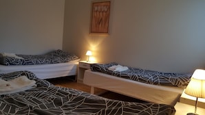 Et værelse med to senge, hver med sengetæppe med mønster, et natbord med lampe samt et ophængt maleri på væggen.