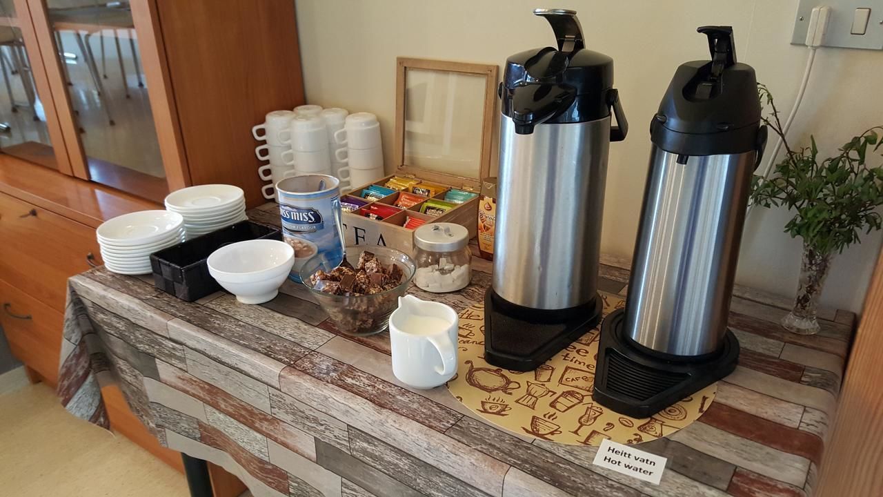 A kitchen counter with coffee makers, a coffee pot, a jar of sugar, and a box of tea bags.