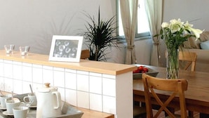 A kitchen with a wooden countertop, a tray with kitchenware, a framed photo, and a vase with flowers.