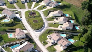 An aerial view of a residential area with houses, roads, and swimming pools.
