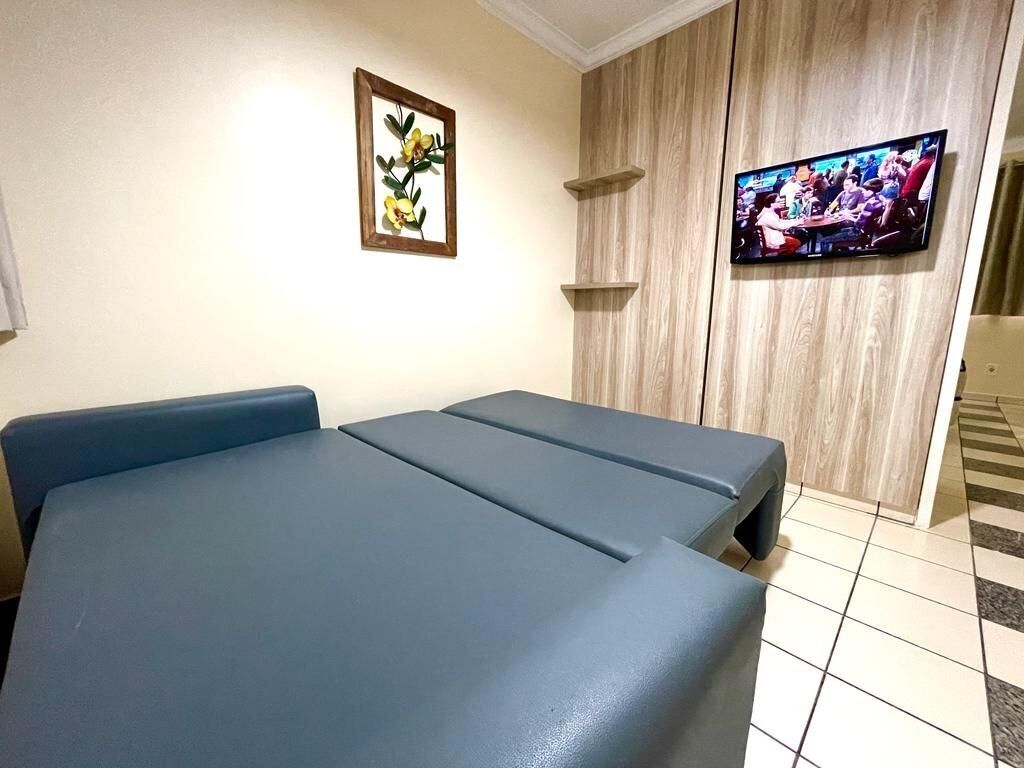 Una habitación con una mesa de masajes, un televisor en la pared y un cuadro enmarcado.