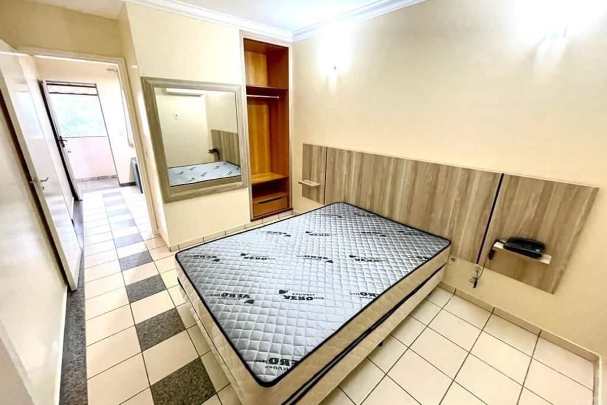 Une chambre à coucher comprenant un lit, une armoire, un miroir et une porte donnant sur une autre pièce.