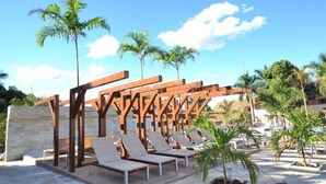 Zona de piscina amb gandules i palmeres.