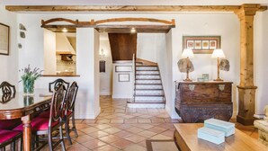Un comedor con una mesa y sillas de madera, una escalera y un aparador de madera.