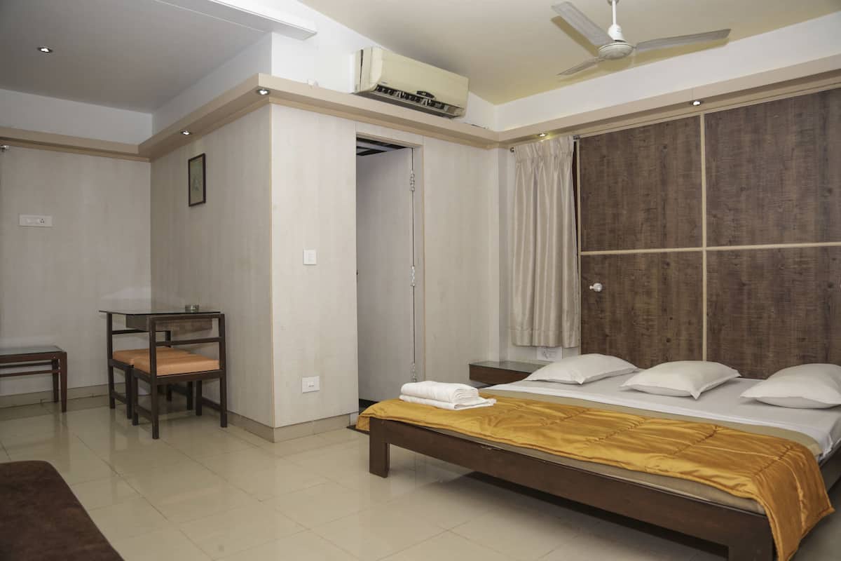 A bedroom with a bed, bedside table, chair, and a wardrobe.