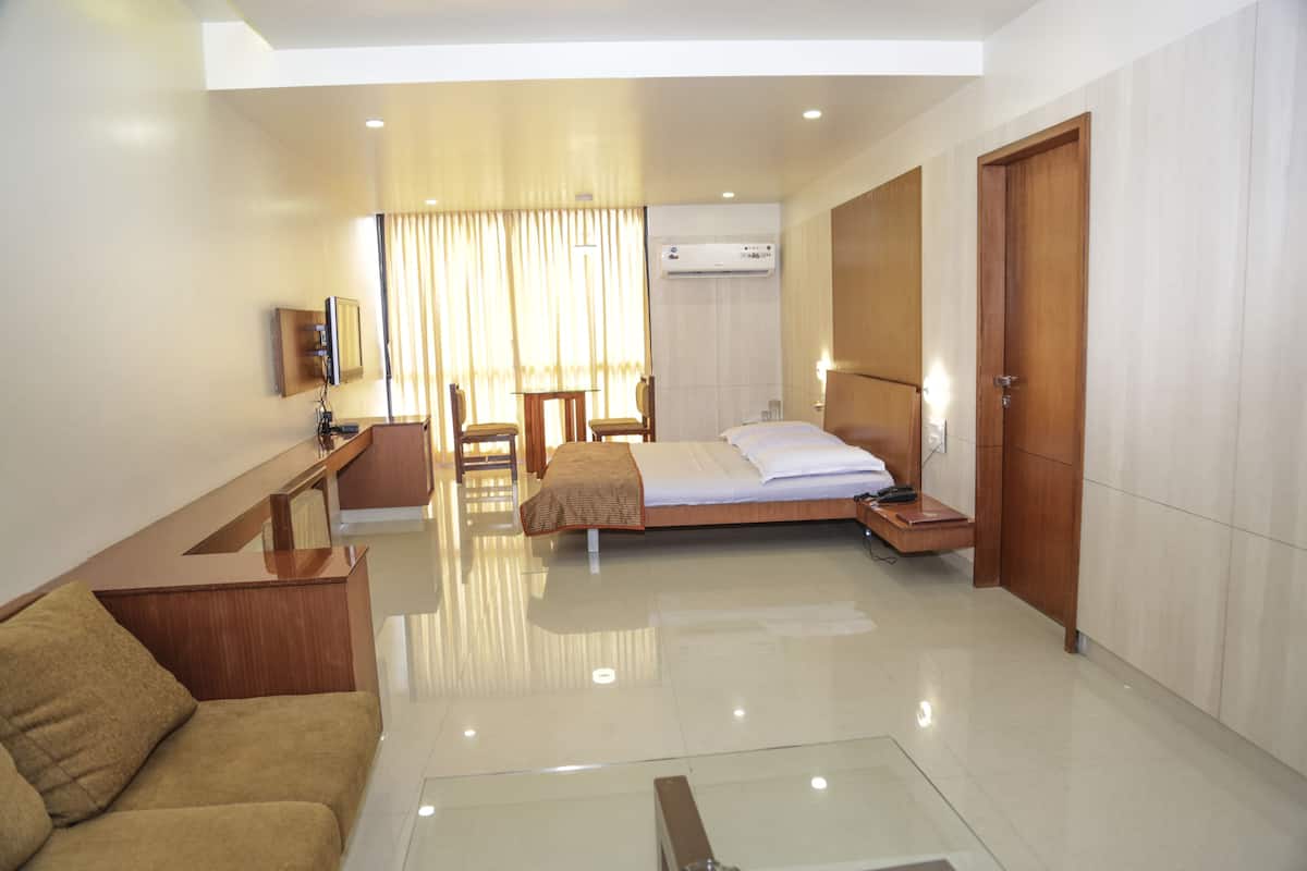 A hotel room with a bed, a desk, a chair, a sofa, and a television.