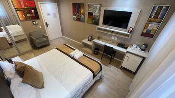 A hotel room with a bed, desk, chair, and a TV.