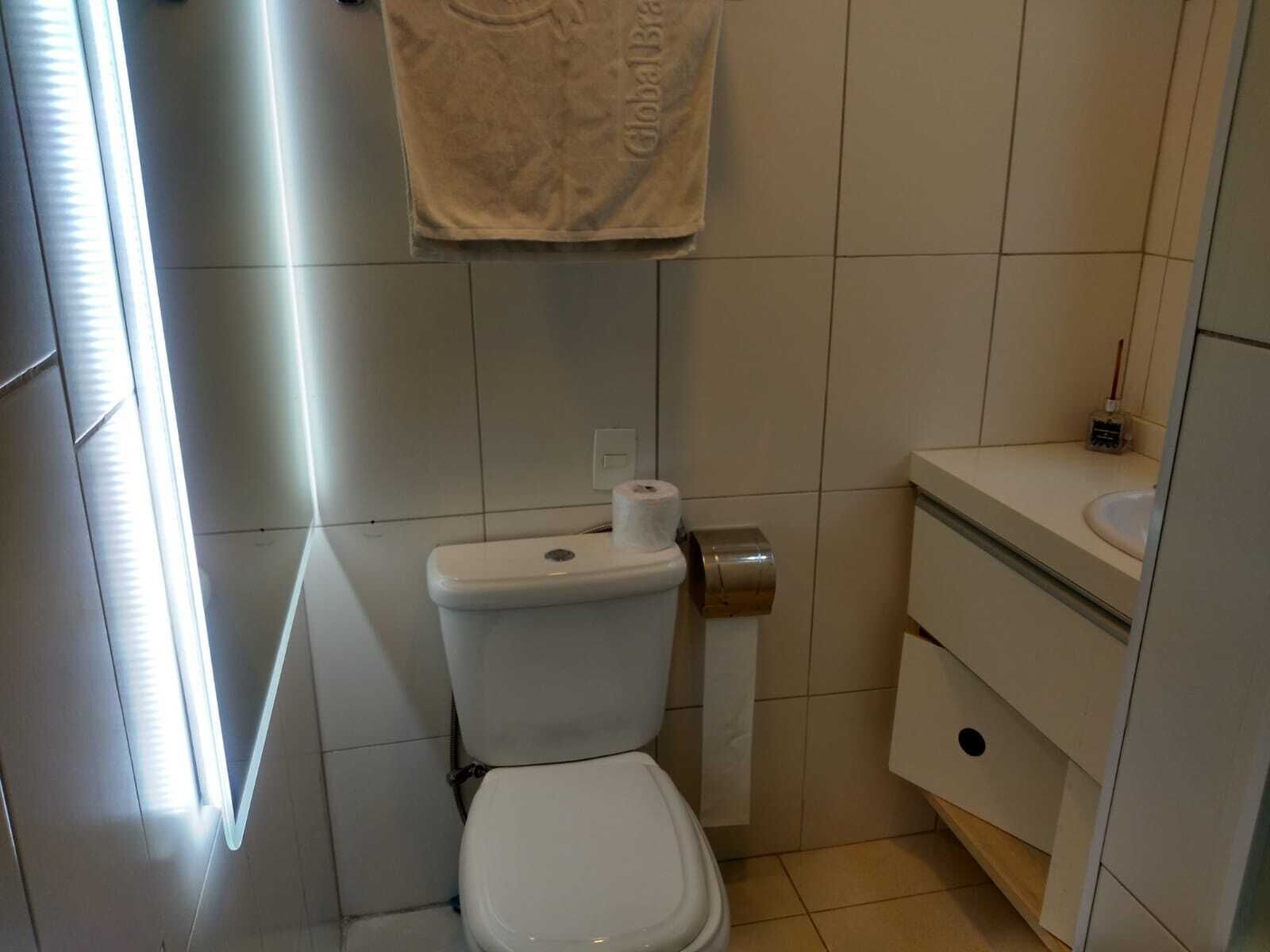 A small bathroom with a toilet, a sink, and a towel hanging on the wall.