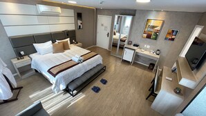 A modern hotel room with a large bed, bedside tables, a desk, a mirror, and a TV.