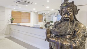 A reception area with a statue, a desk, and a computer.