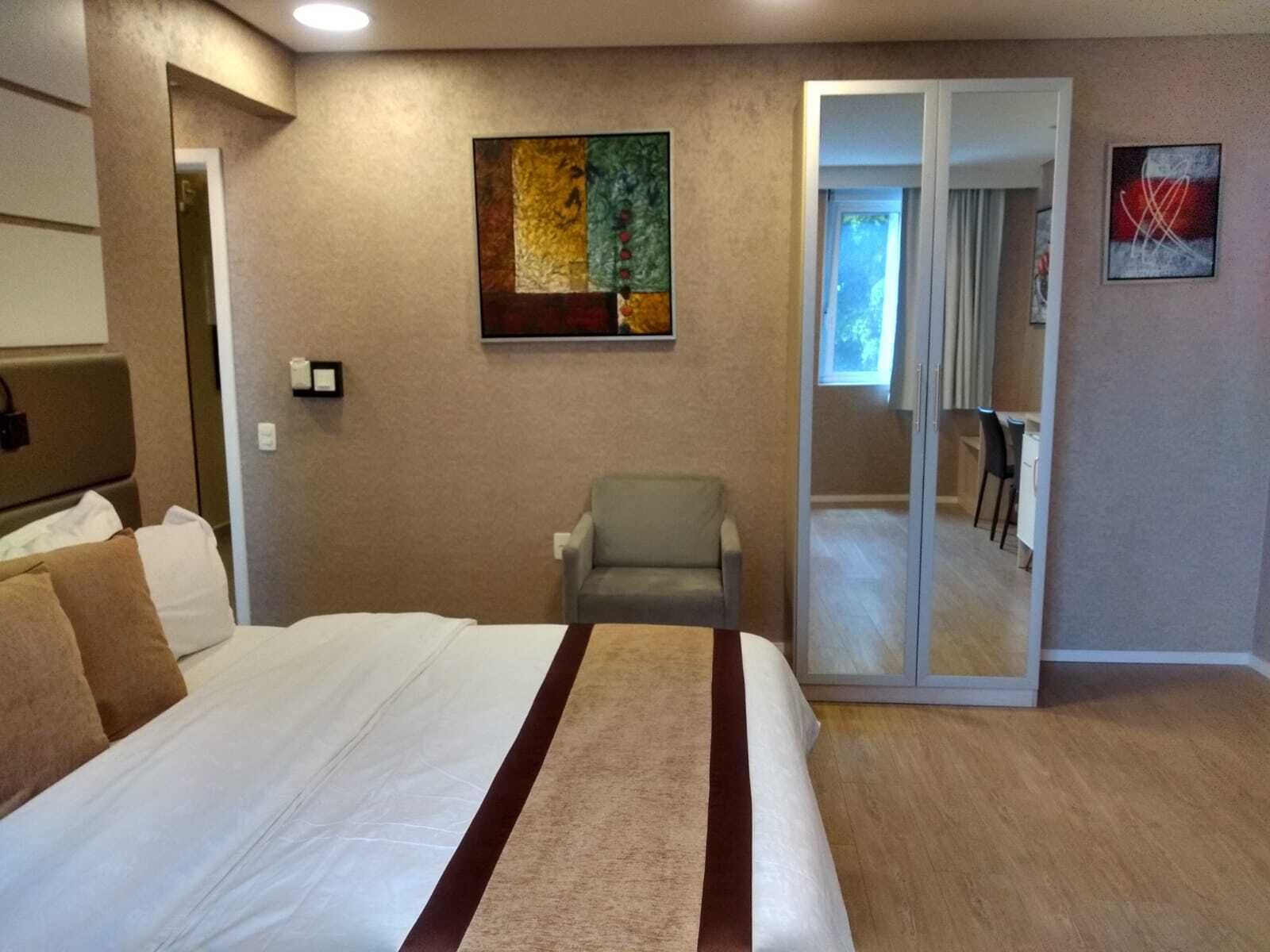 Ein Hotelzimmer mit einem Bett, einem Sessel, einer Schiebetür zu einem Balkon und Bildern an den Wänden.