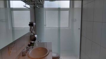 Un baño moderno con un espejo grande, un lavabo y una zona de ducha.
