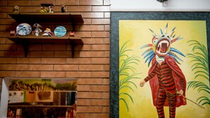 A brick wall with shelves holding decorative items and a framed painting of a colorful animal. - Hotel Acapulco (Panama City)