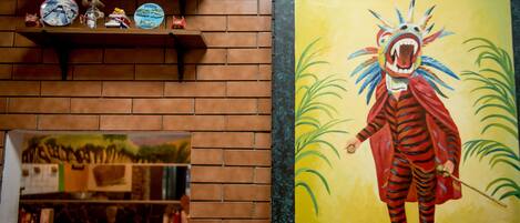 A brick wall with shelves holding decorative items and a framed painting of a colorful animal.