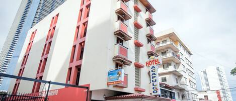 Un hotel con una fachada llamativa de rojo y blanco, varios balcones y un letrero que indica que es un establecimiento panameño.