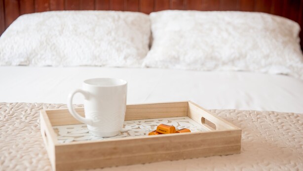 A wooden tray with a white mug and orange objects on a textured bedspread. - Hotel Acapulco (Panama City)