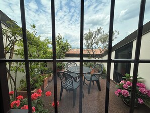 A balcony with a table and chairs, surrounded by potted plants and flowers. - Atelier di Charme (Verona)