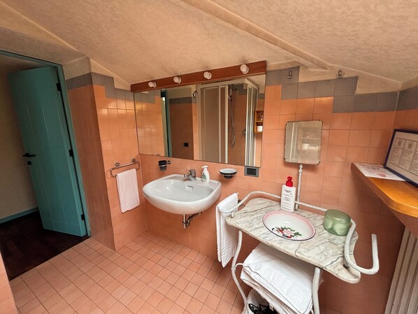 A bathroom with a sink, mirror, towel rack, and a small shelf with toiletries.