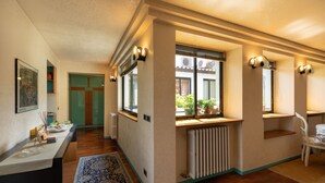 Un pasillo con un radiador, una ventana que ofrece vistas al exterior y una silla cerca de la ventana.