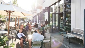 Un café al aire libre con mesas, sillas y sombrillas.