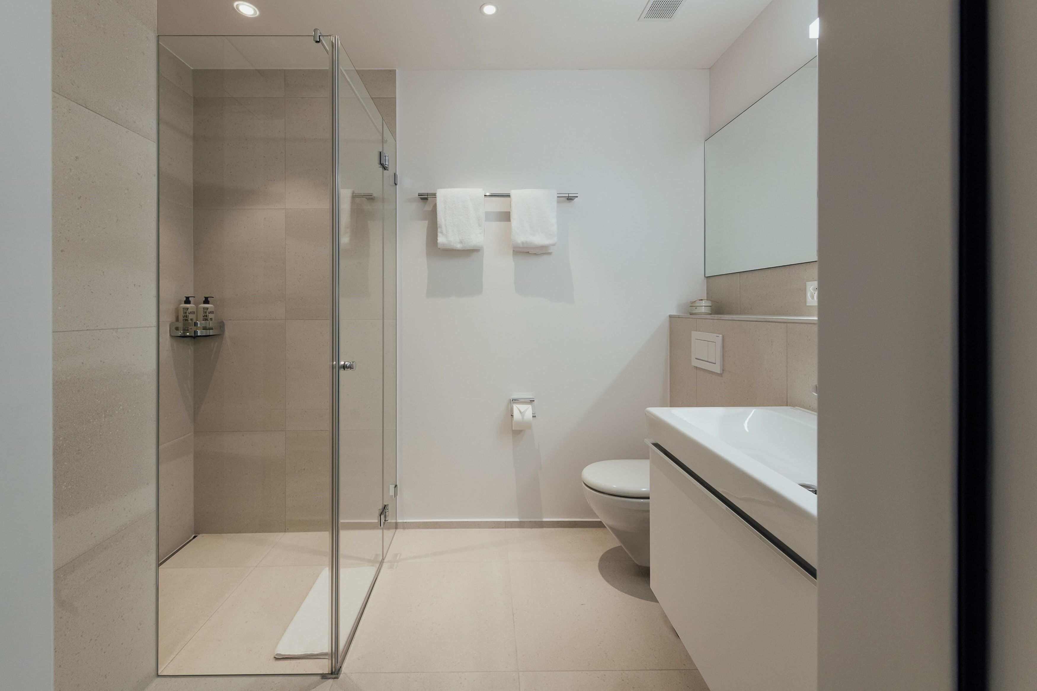 Ein modernes Badezimmer mit Duschkabine aus Glas, Toilette und Waschbecken.