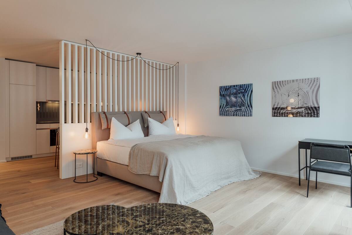 Un dormitorio moderno con cama, mesita de noche y una obra de arte en la pared.