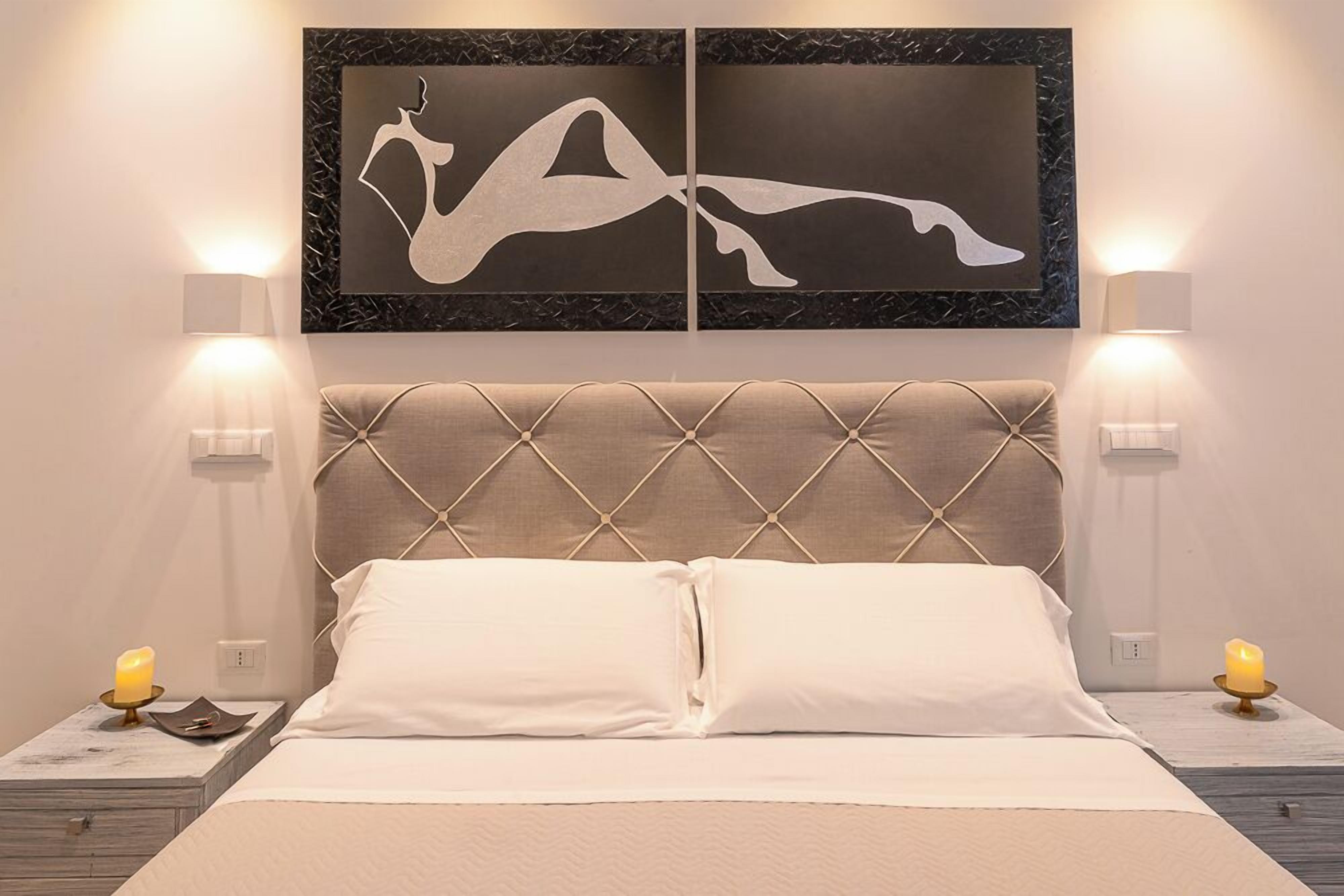 A neatly arranged bedroom with a tufted headboard, two bedside tables with lamps, and a wall-mounted artwork above the bed.