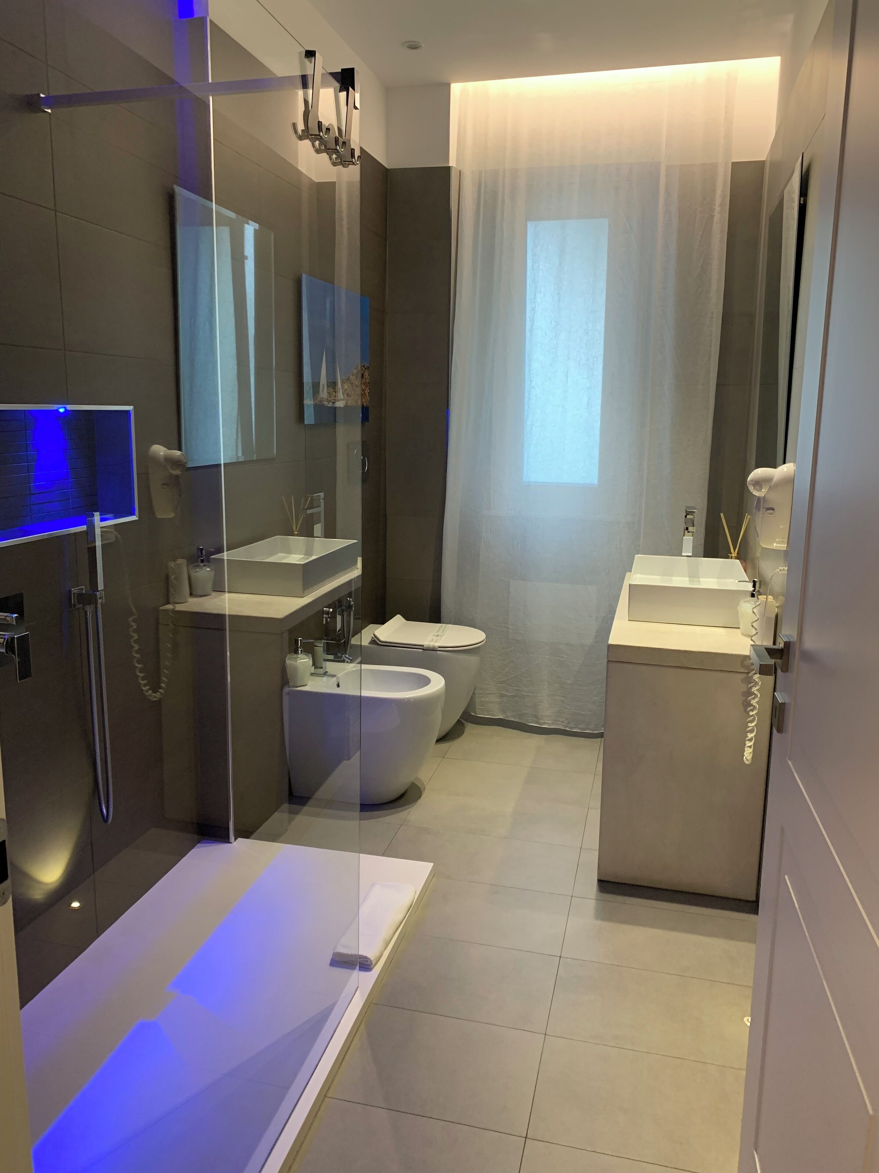 Un bagno moderno con doccia a schermo di vetro, una vasca freestanding, un water e un lavabo.