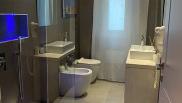 Un bagno moderno con doccia a schermo di vetro, una vasca freestanding, un water e un lavabo.
