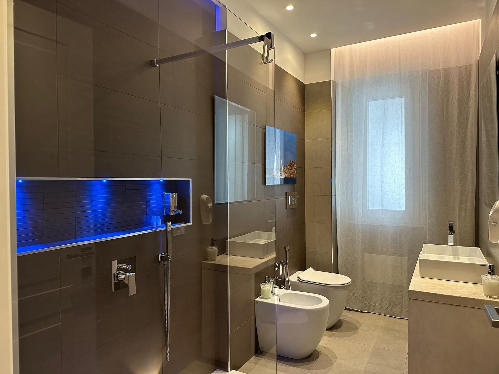 A modern bathroom with a glass shower enclosure, a toilet, and a bidet.