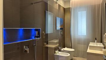 A modern bathroom with a glass shower enclosure, a toilet, and a bidet.