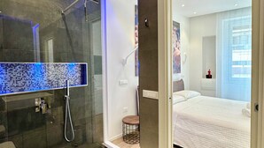 A modern bathroom with a glass-enclosed shower, a digital mirror, and a separate toilet. - J&O' Luxury Suite (Cagliari)